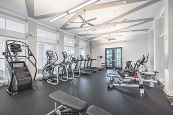 A spacious gym with a variety of equipment including treadmills, stationary bikes, and weight machines.